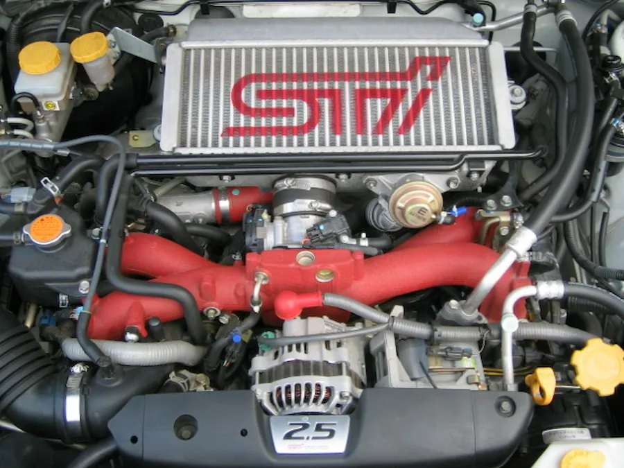 Detailed view of a Subaru Forester STI engine bay with red intake manifold.